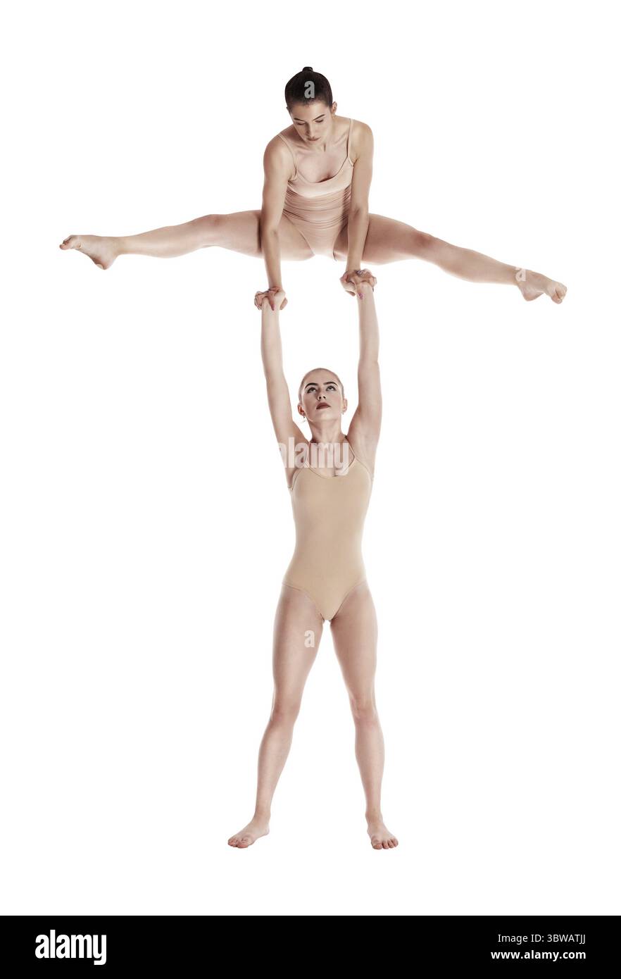 Due donne forti ginnasti in beige leotards esecuzione di elementi complessi di ginnastica usando il supporto ponendo isolati su bianco. Concetto di sport fitn Foto Stock