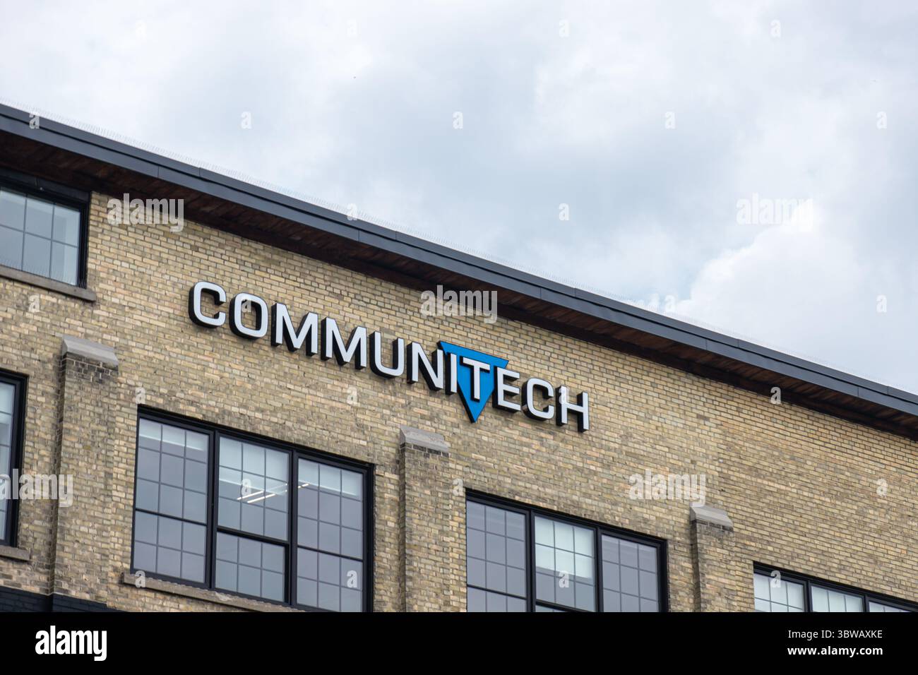 Kitchener, ON, CANADA - 5 agosto 2024: Logo Communitech su un edificio in mattoni con grandi finestre sotto il cielo coperto. Foto Stock