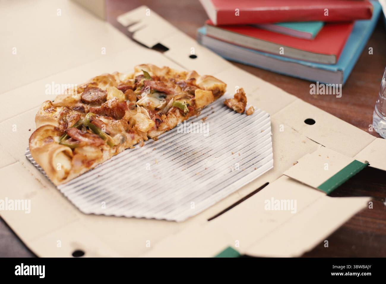 Pezzi di pizza sul tavolo. La Pizza sul tavolo con libri e bevande per gli studenti che desiderano celebrare la festa dopo l'esame. Tagliare la pizza in scatola di consegna. Foo Foto Stock