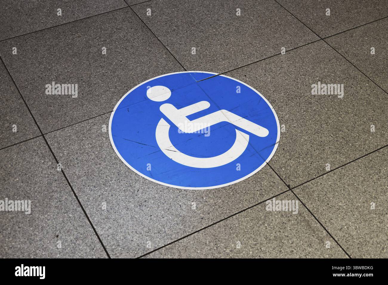 Icona blu di accessibilità per sedie a rotelle posizionata a terra, con indicazione delle strutture o degli spazi pubblici Foto Stock