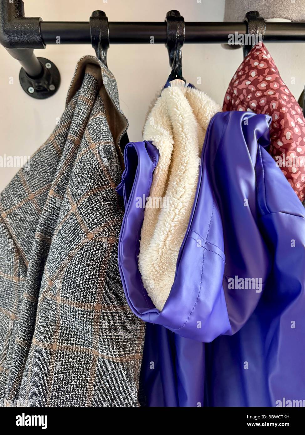 I cappotti e le giacche per bambini sono appesi ordinatamente su un appendiabiti del corridoio. La scena suggerisce calore, routine quotidiane e il trambusto accogliente della vita familiare a casa Foto Stock