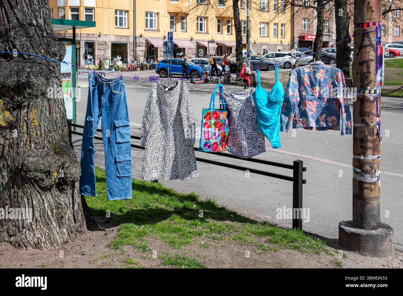 Oggetti usati appesi alla linea di abbigliamento al mercato delle pulci pop-up di Karhupuisto nel quartiere Kallio di Helsinki, Finlandia Foto Stock