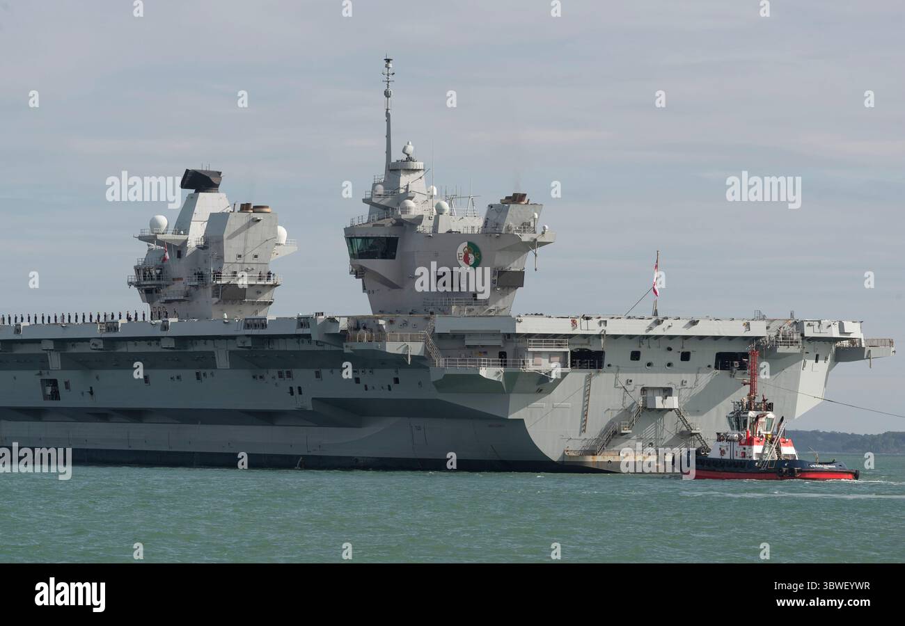 Il Solent Portsmouth Inghilterra Regno Unito. 16.07.2025. HMS Queen Elizabeth con rimorchiatori che navigano sul Solent in partenza da Portsmouth il porto di origine delle portaerei. REGNO UNITO Foto Stock