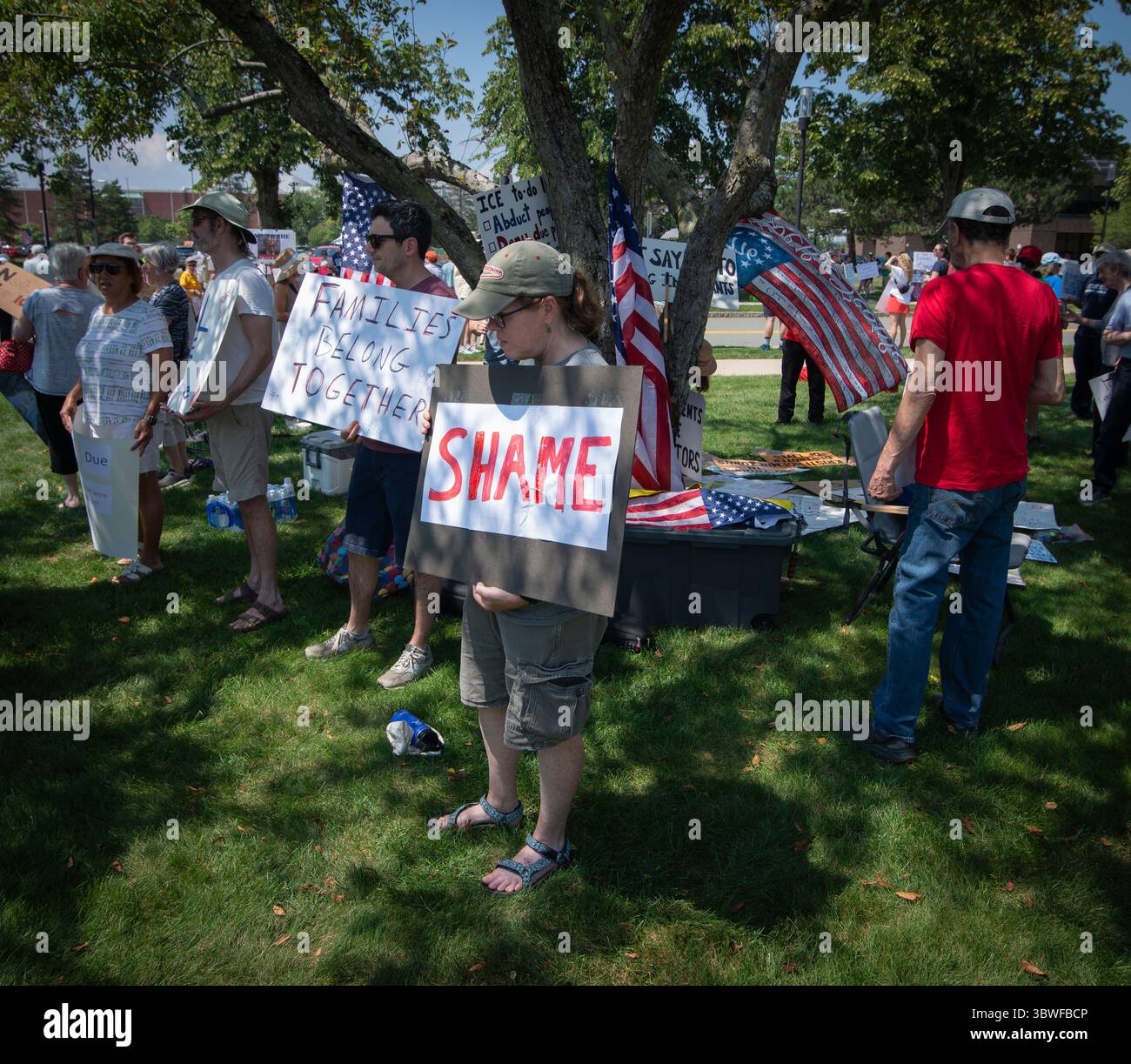 Burlington, Massachusetts, Stati Uniti. 16 luglio 2025. 13a manifestazione settimanale «testimoniare» al di fuori della struttura del New England per l’immigrazione e l’applicazione delle dogane (ICE) a Burlington. La struttura, 26 km a nord-ovest di Boston, ospita persone detenute dal GHIACCIO negli stati di Rhode Island, Connecticut, Massachusetts, New Hampshire, Maine e Vermont. Centinaia di persone hanno partecipato alla manifestazione pacifica contro L'ICE, Donald Trump e la sua attuale amministrazione al di fuori della struttura. Dimostratori all'ombra. Crediti: Chuck Nacke / Alamy Live News Foto Stock
