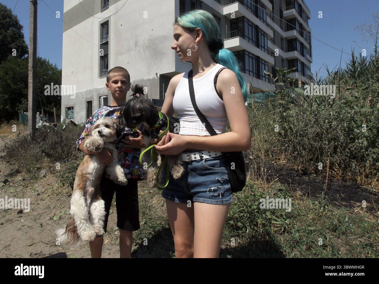 Non esclusiva: Un ragazzo e una ragazza tengono i cani fuori da un blocco di appartamenti danneggiati dalla caduta di detriti di droni russi, Dnipro, Ucraina, 15 luglio 202 Foto Stock