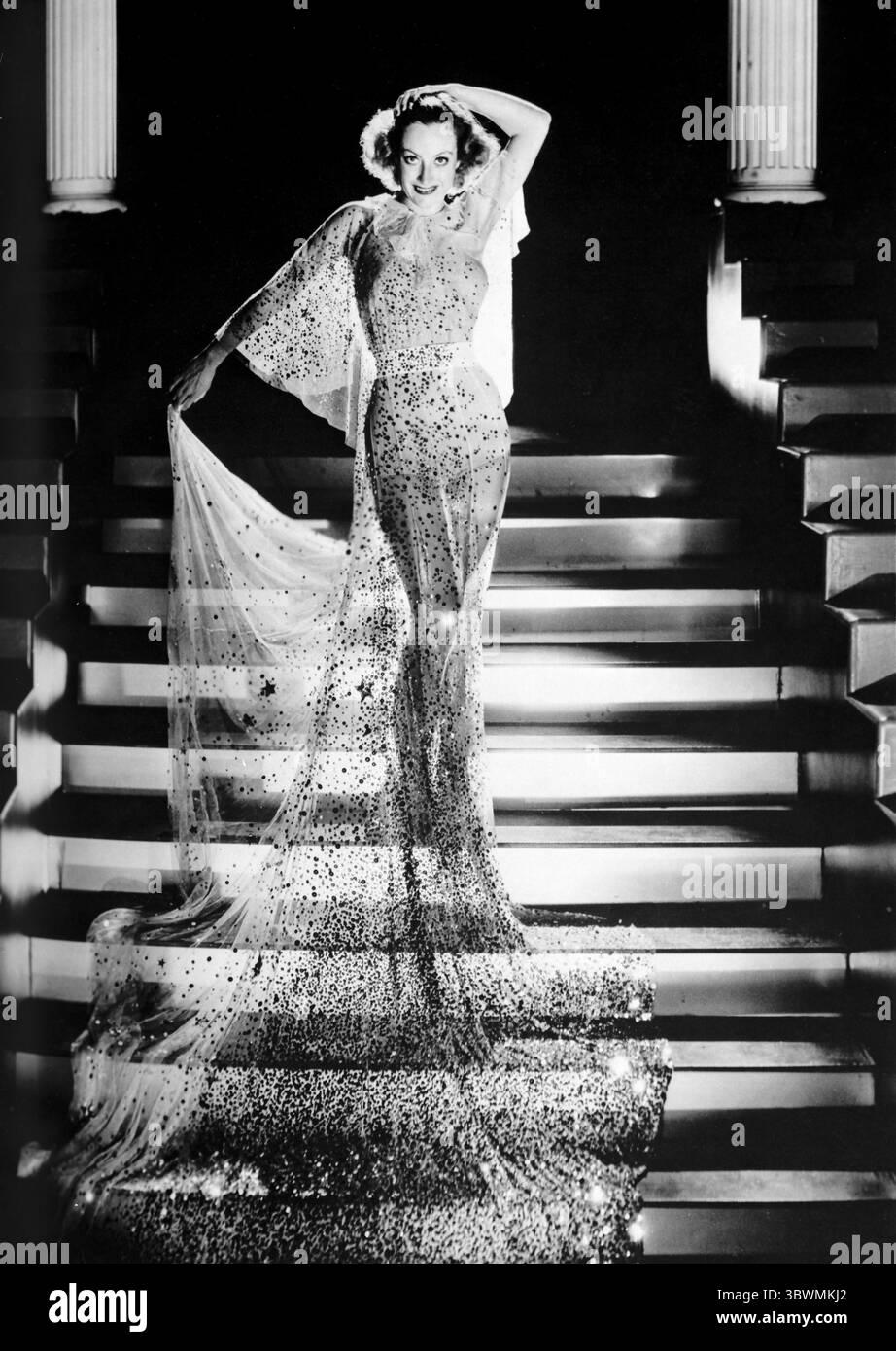 Joan Crawford indossa un abito lungo mentre è sulle scale in un Ritratto classico. Joan Crawford è stata un'attrice statunitense, di film e televisione, ballerina e cantante. Crawford iniziò come coro a Broadway prima di ottenere un contratto con la MGM nel 1925. Era una grande star di film stracci-ricchi, in cui le persone hanno raggiunto il successo e il romanticismo attraverso il duro lavoro. Anche se i suoi film degli anni '1920 ebbero molto successo, alla fine degli anni '1930, era stata soprannominata Box Office Poison. Tuttavia, in una vera storia stracci-ricchezza, Crawford fece una pinna di ritorno 1945 con Mildred Pierce e vinse anche l'Oscar per la migliore A Foto Stock