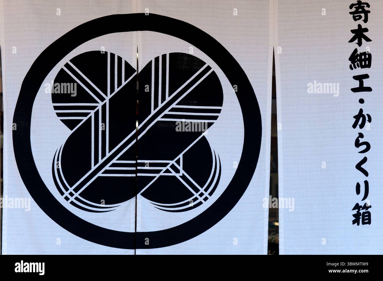 Noren con la famiglia giapponese "kamon" (cresta) "Maru ni Chigai Takanoha" (丸に違鷹羽) ha due piume di falco incrociate in un cerchio spesso usato dai samurai, in Giappone. Foto Stock