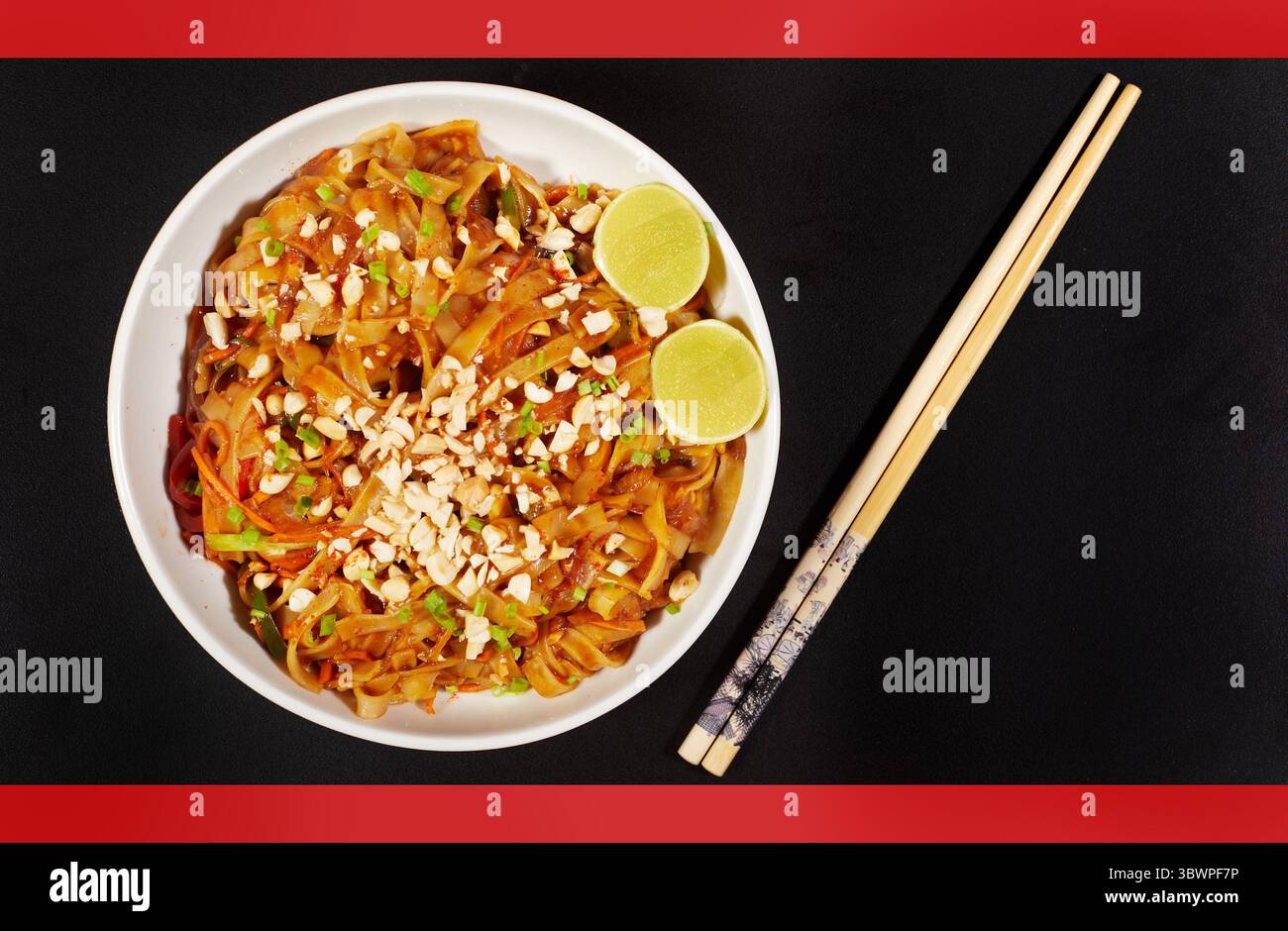 Spaghetti thailandesi ricchi di sapore conditi con salsa piccante e piccante, conditi con arachidi tritate e lime fresco. Un piatto vibrante e aromatico perfetto per gli amanti Foto Stock