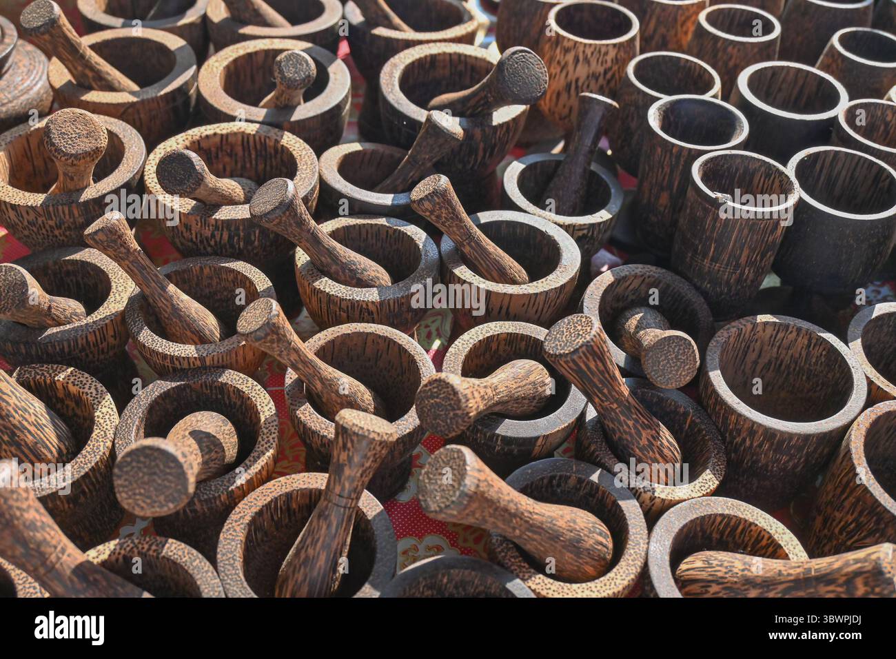 Collezione di mortai e pestelli in legno artigianali esposti in vendita in un mercato locale sotto la luce naturale del sole. Foto Stock