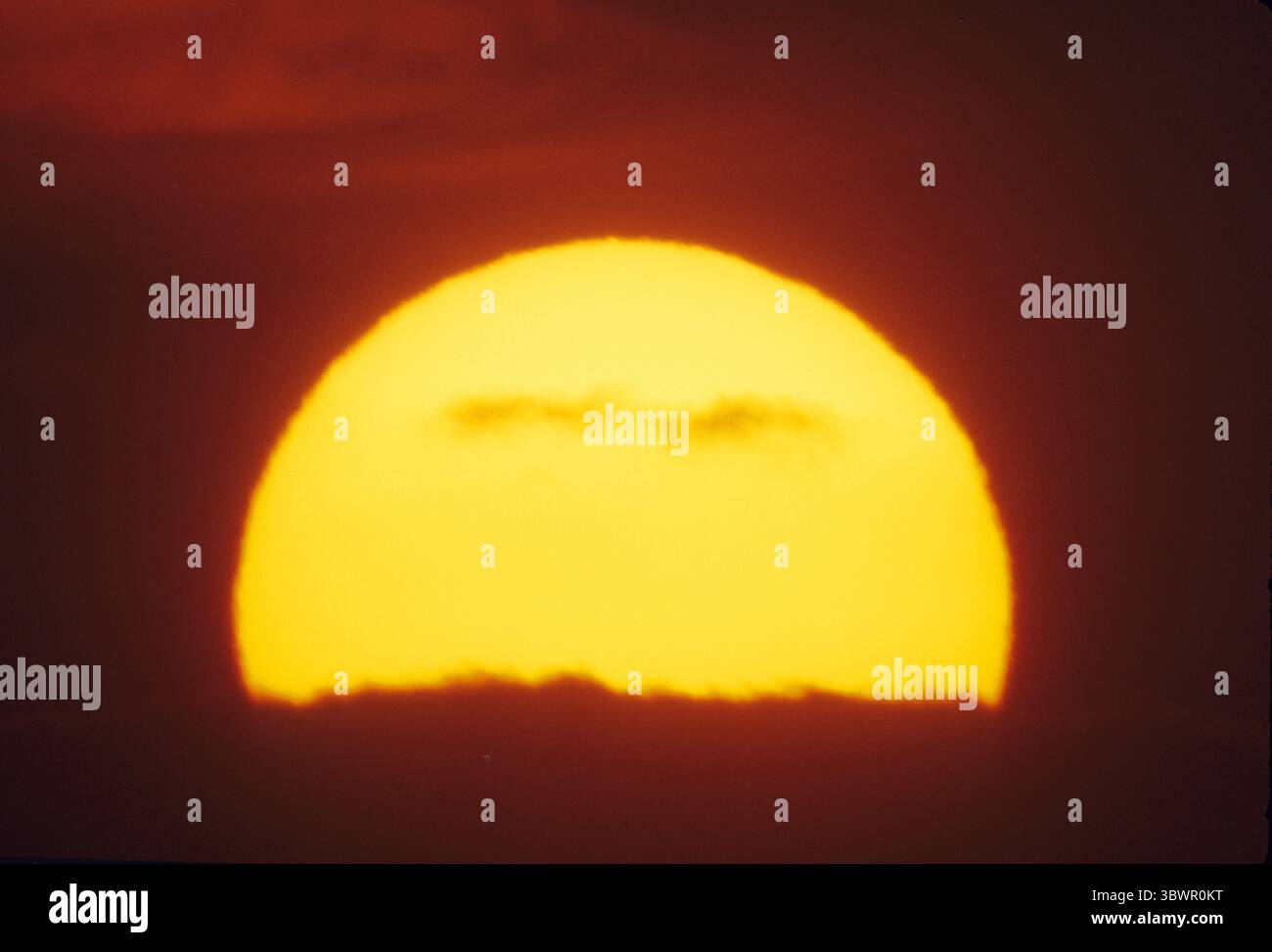 tramonto, un enorme semicerchio di sole, simbolo di calore ed energia luminosa Foto Stock