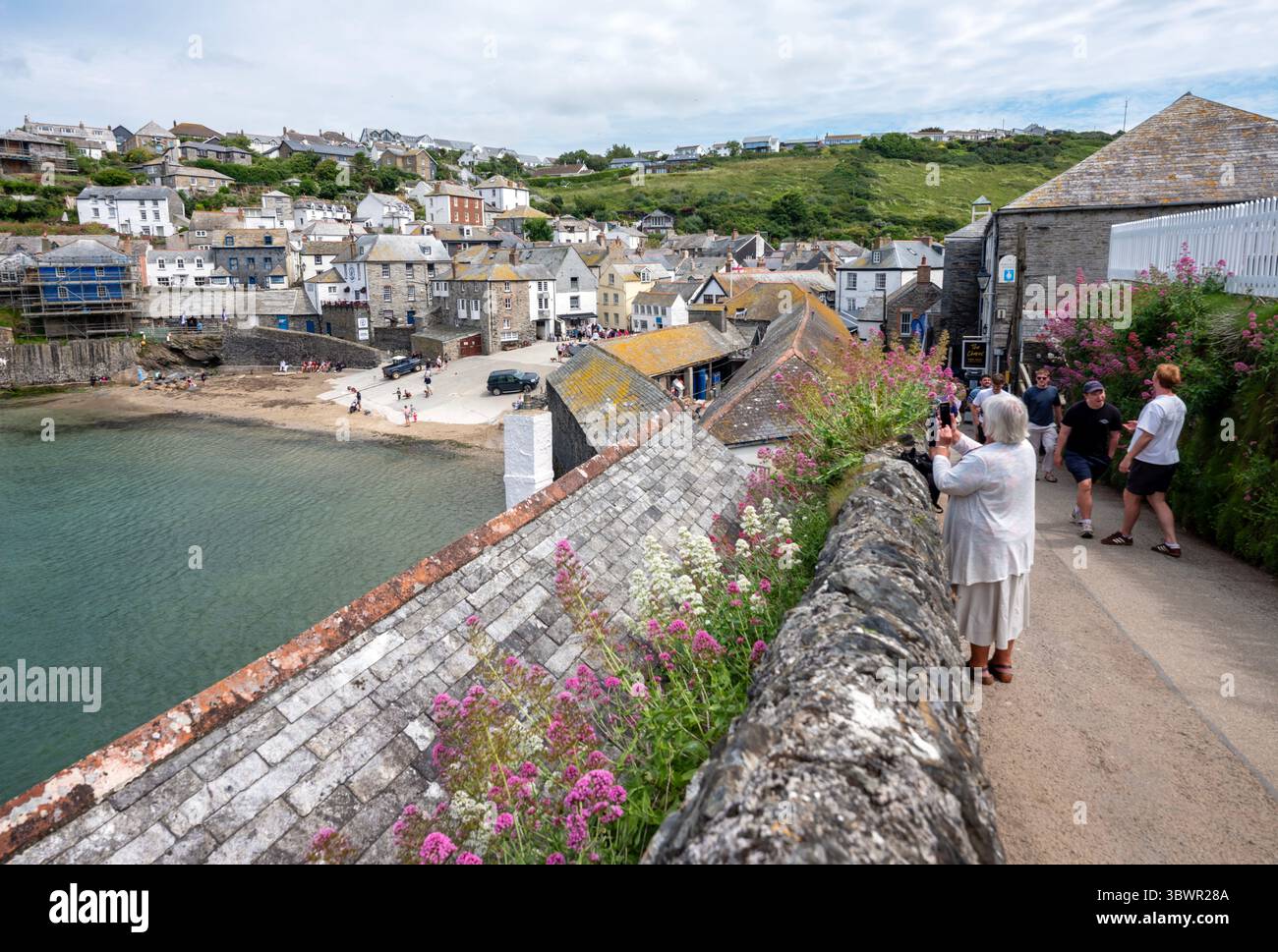 port isaac, inghilterra, 22 giugno 2025: turisti sopra il porto nel villaggio cornico di port isaac in un giorno di primavera soleggiato Foto Stock