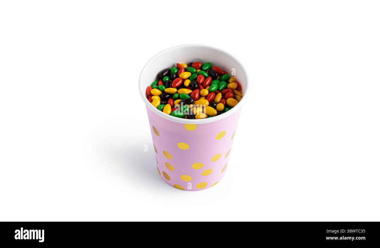 Tazza di carta con semi di girasole di cioccolato colorati isolati su sfondo bianco. Foto di alta qualità Foto Stock