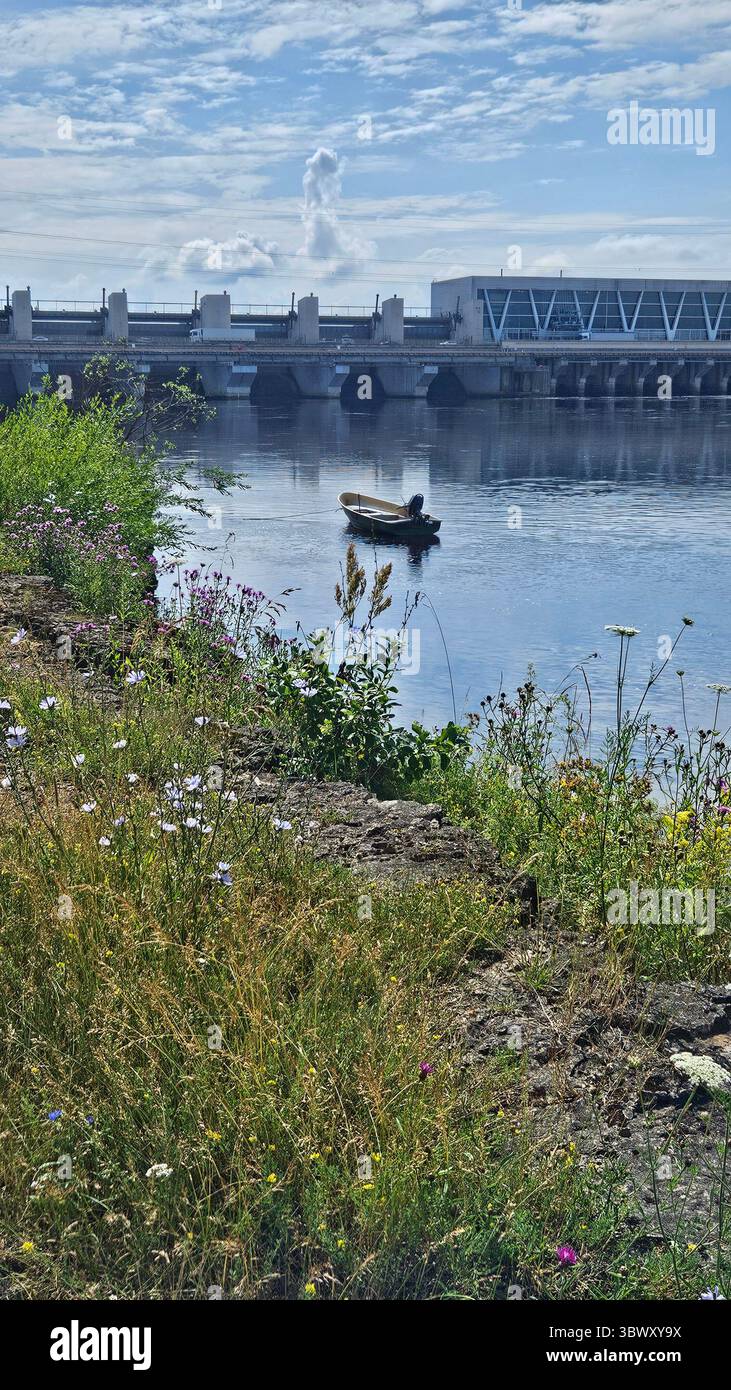 Barca sul fiume vicino alla diga idroelettrica. Riga HES.Lettonia.17.07.2025 - Immagine stock catturata con smartphone