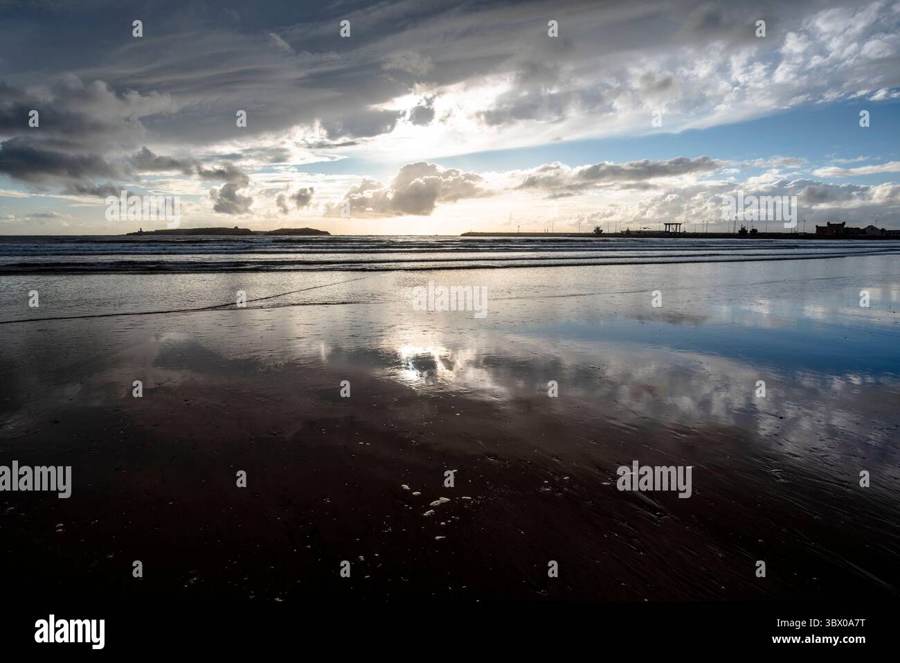 Tramonto sulle vaste spiagge di Essaouira con cieli blu, nuvole bianche e onde che si infrangono sulla riva del Marocco Foto Stock