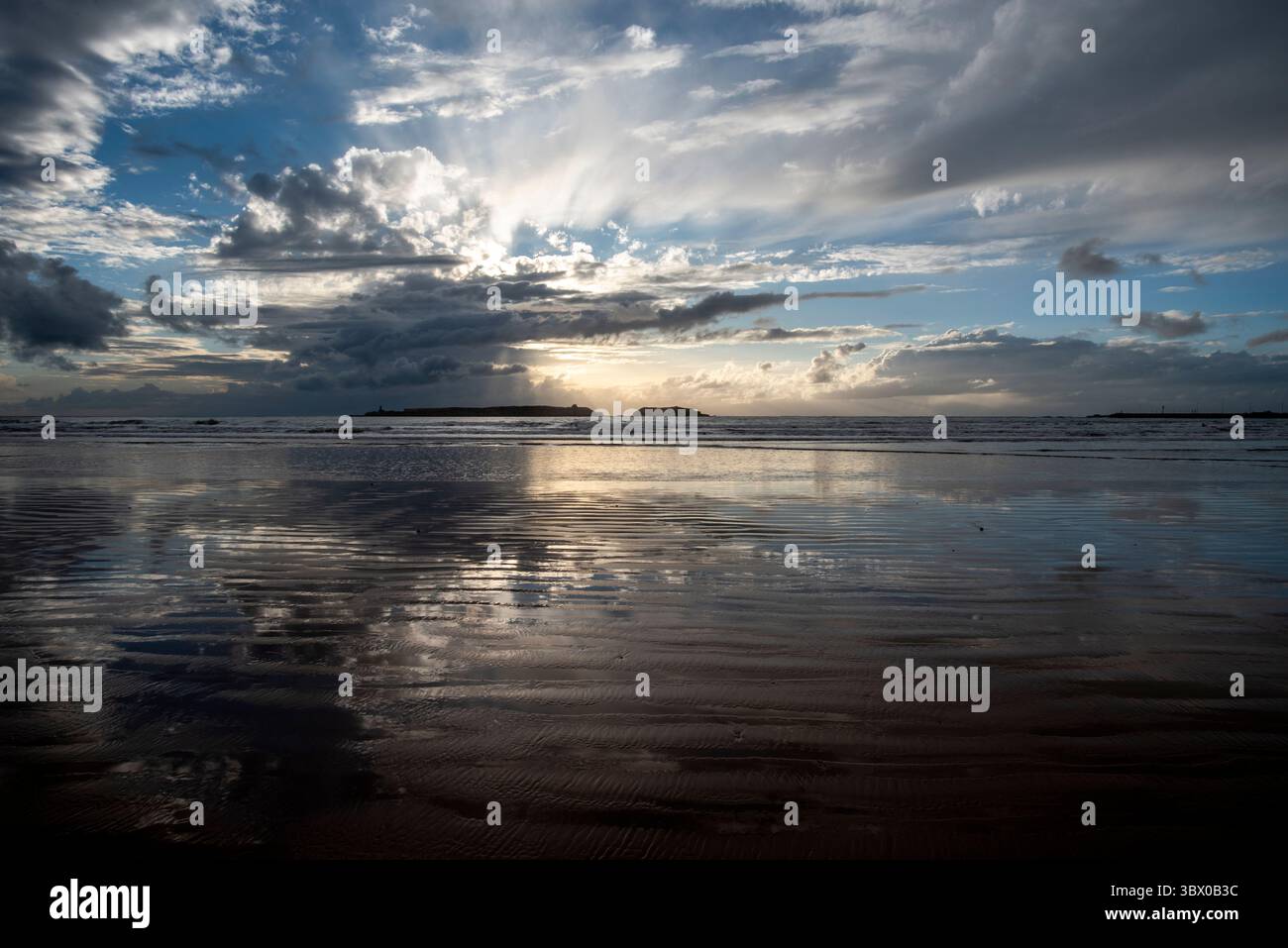 Tramonto sulle vaste spiagge di Essaouira con cieli blu, nuvole bianche e onde che si infrangono sulla riva del Marocco Foto Stock