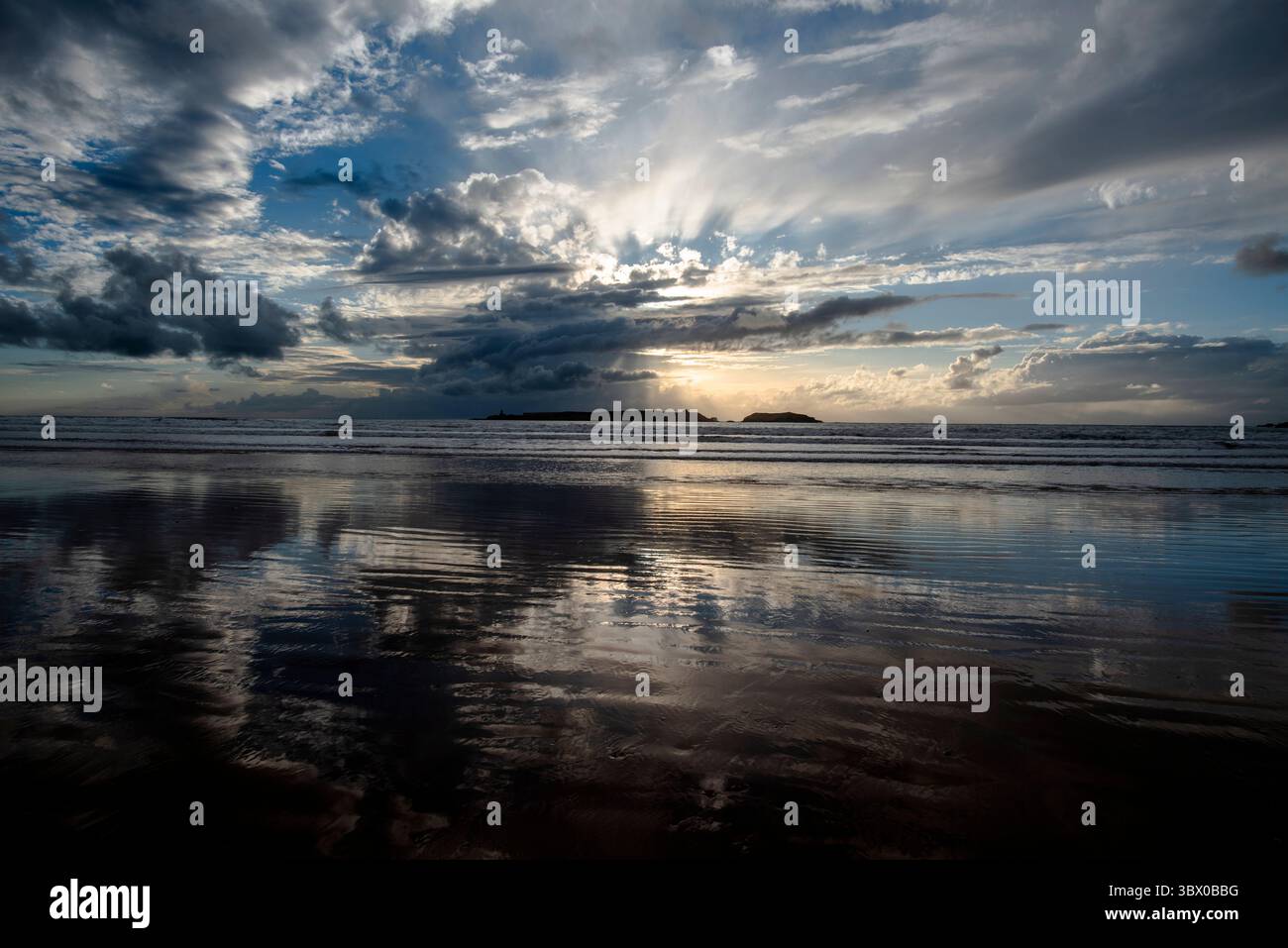 Tramonto sulle vaste spiagge di Essaouira con cieli blu, nuvole bianche e onde che si infrangono sulla riva del Marocco Foto Stock