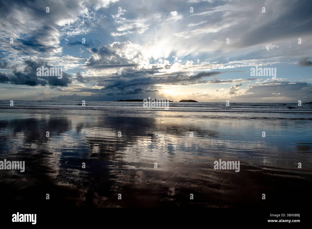 Tramonto sulle vaste spiagge di Essaouira con cieli blu, nuvole bianche e onde che si infrangono sulla riva del Marocco Foto Stock