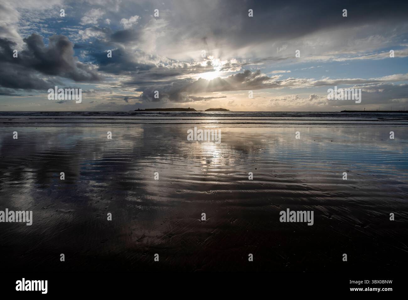 Tramonto sulle vaste spiagge di Essaouira con cieli blu, nuvole bianche e onde che si infrangono sulla riva del Marocco Foto Stock
