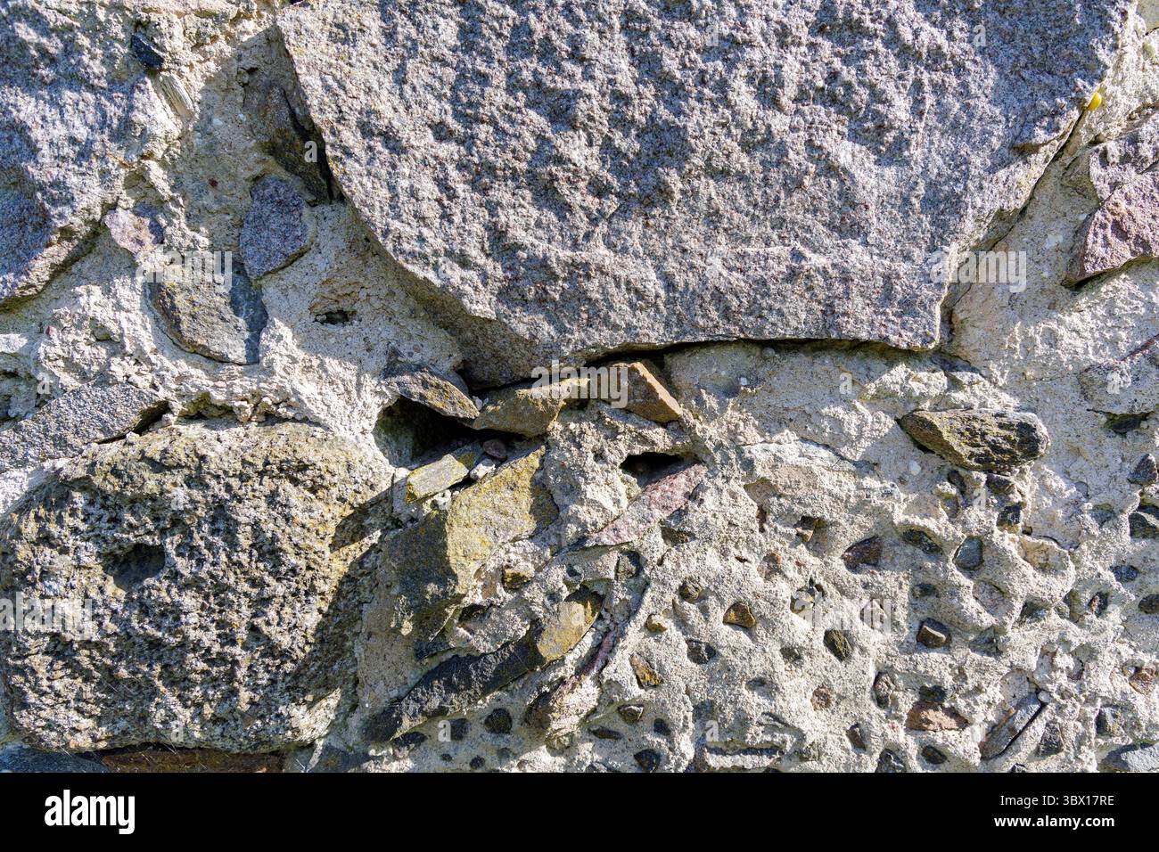 Primo piano di un'aspra parete di pietra, che mostra rocce e Malta intemperie, ideale per sfondi e temi storici. Foto Stock Primo piano di un'aspra parete di pietra, che mostra rocce e Malta intemperie, ideale per sfondi e temi storici. Foto Stock
