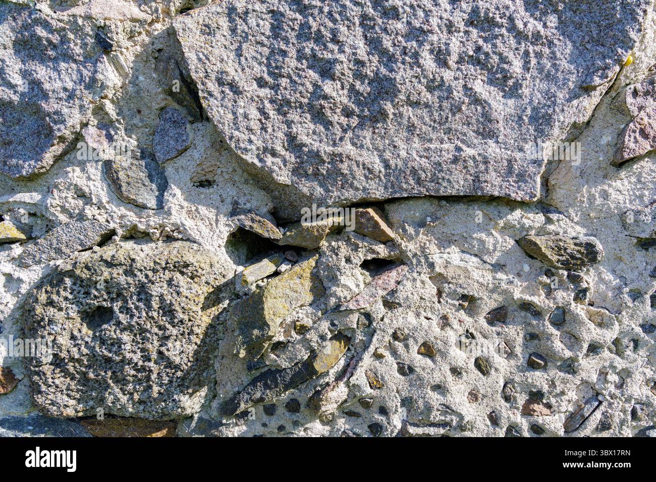 Primo piano di un'aspra parete di pietra, che mostra rocce e Malta intemperie, ideale per sfondi e temi storici. Foto Stock Primo piano di un'aspra parete di pietra, che mostra rocce e Malta intemperie, ideale per sfondi e temi storici. Foto Stock
