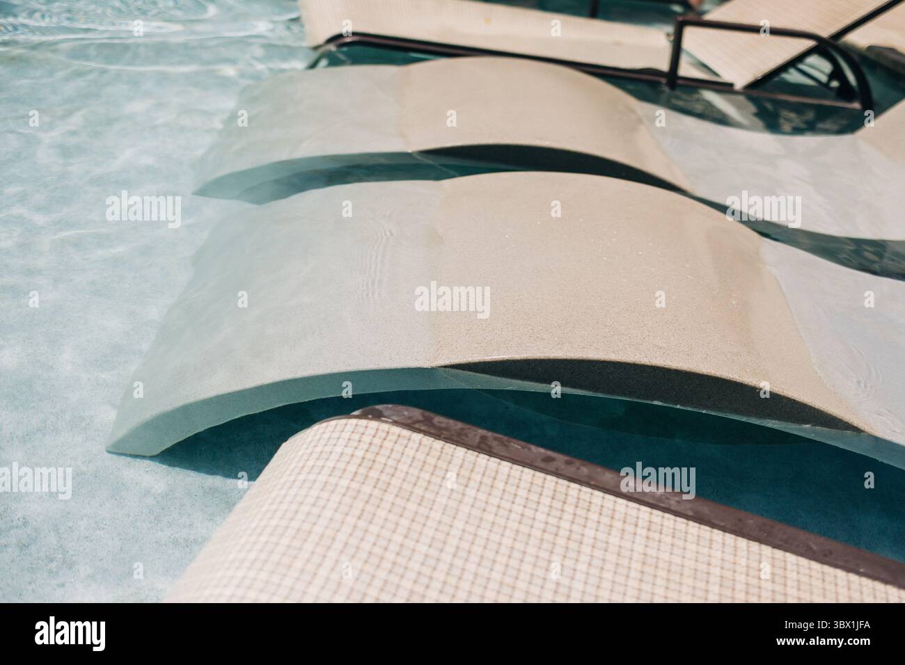 Splendida piscina con eleganti lettini immersi in acque cristalline, perfetta per rilassarsi in una calda giornata estiva. Foto Stock