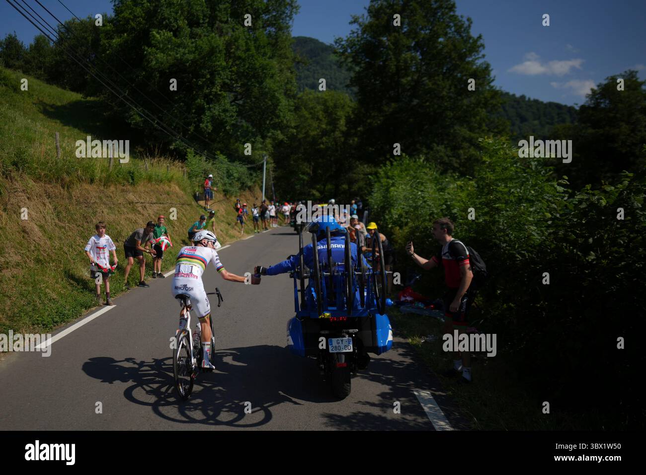 Stage winner Slovenia's Tadej Pogacar is handed a water bottle by the neutral service motorcycle during the twelfth stage of the Tour de France cycling race over 180.6 kilometers (112.2 miles) with start in Auch and finish in Hautacam, France, Thursday, July 17, 2025. (AP Photo/Thibault Camus) Foto Stock