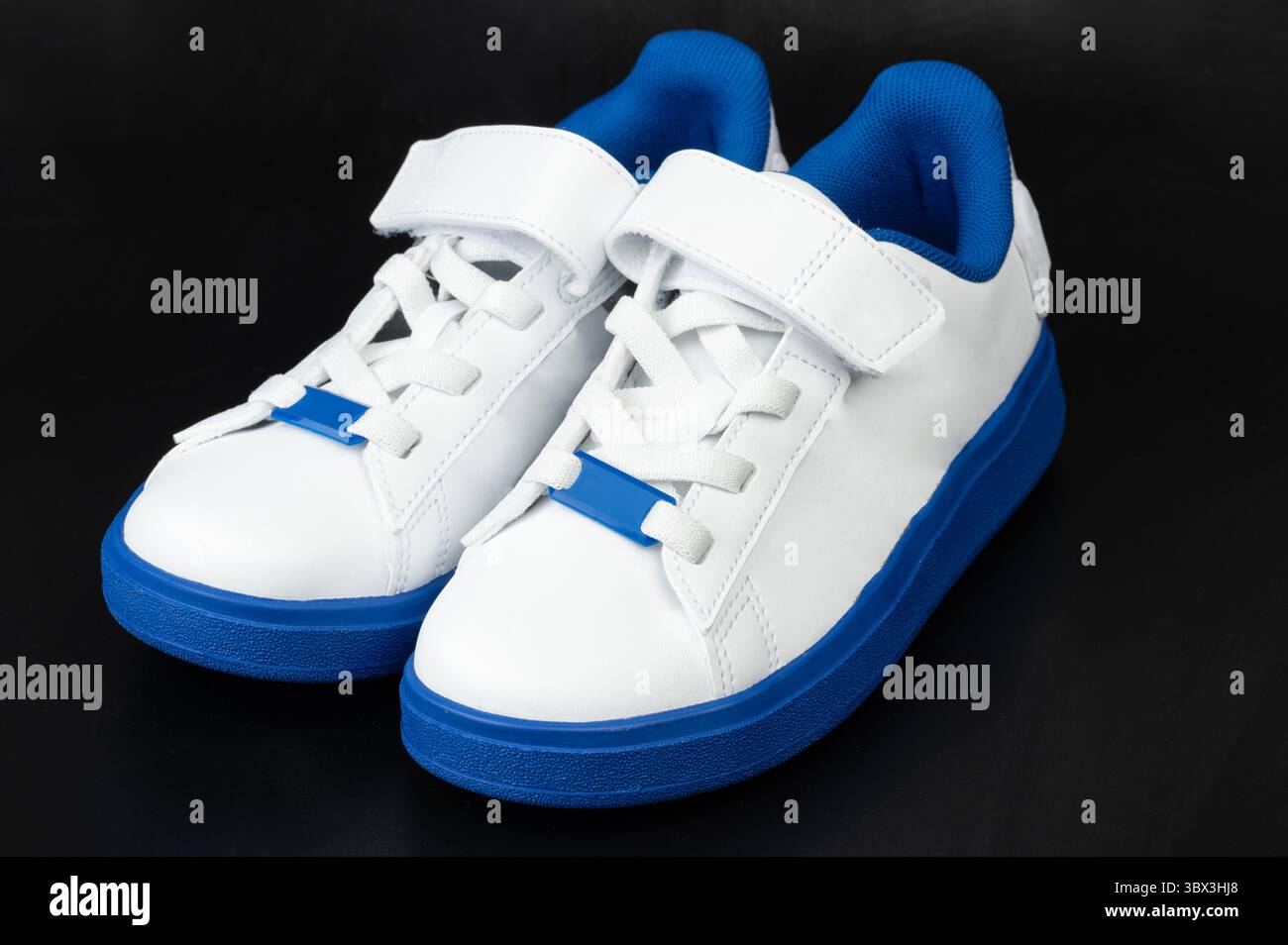 Le sneaker alla moda sono caratterizzate da tomaia bianca con dettagli blu e una pratica tracolla per una vestibilità comoda. Perfetto per uscite informali. Foto Stock