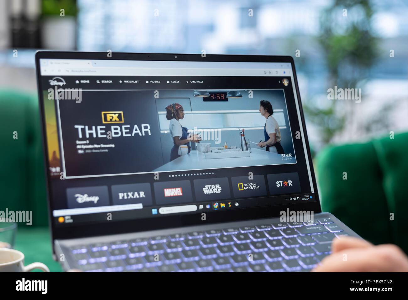Bucarest, Romania - 30 luglio 2024 - l'uomo si prepara a guardare l'Orso su Disney Plus, rilassandosi nel suo ufficio e utilizzando la piattaforma di streaming sul portatile per guardare le serie tv preferite. Foto Stock