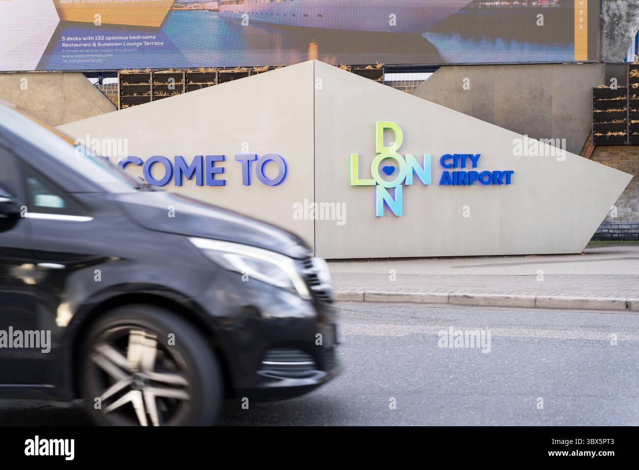 Cartello di benvenuto all'aeroporto di London City, l'unico importante aeroporto di Londra che offre servizio di rientro gratuito per i passeggeri - Vista parziale dell'auto che entra nel Frame Foto Stock