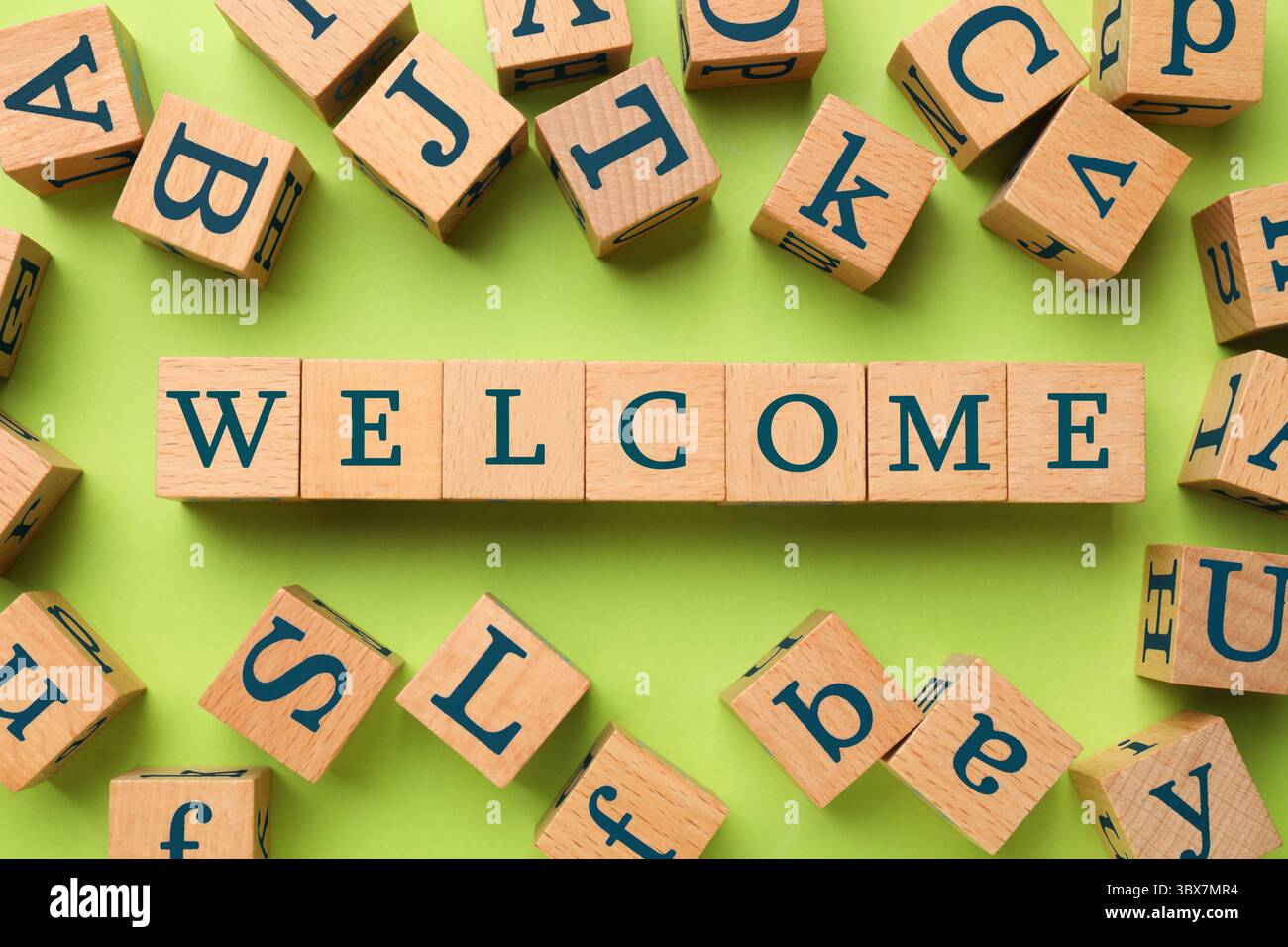 Parola di benvenuto in cubi di legno su sfondo verde chiaro, piano Foto Stock