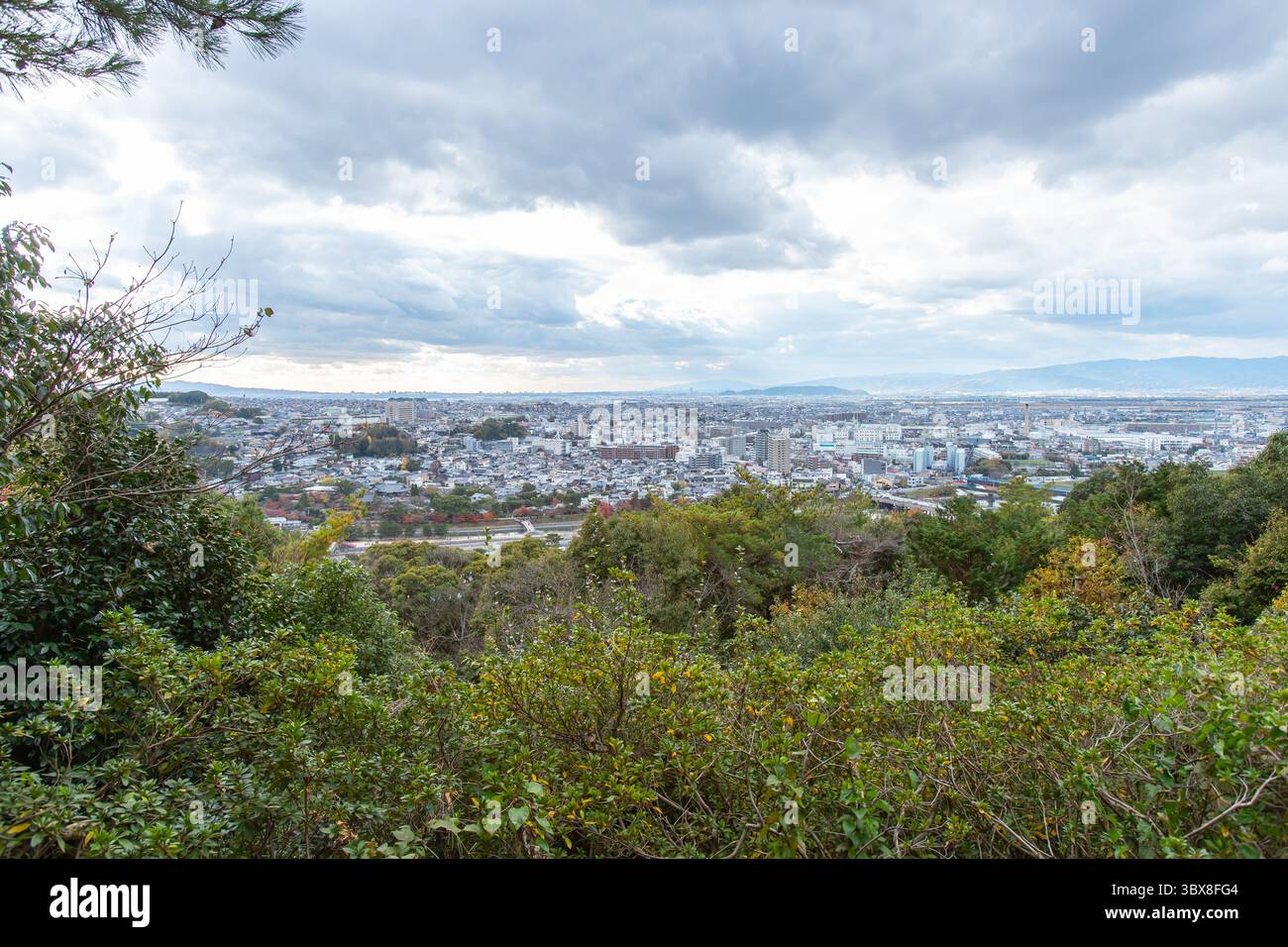 Vista sopraelevata da Daikichiyama a Uji, in Giappone, che mostra la città sotto spettacolari cieli nuvolosi con vegetazione e colline circostanti. Foto Stock
