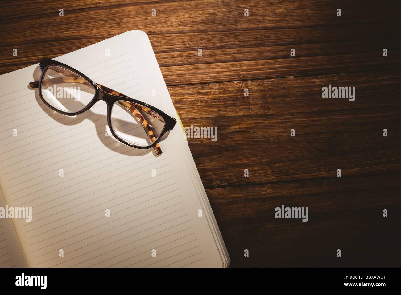 Occhiali da vista su un libro bianco su un tavolo di legno Foto Stock