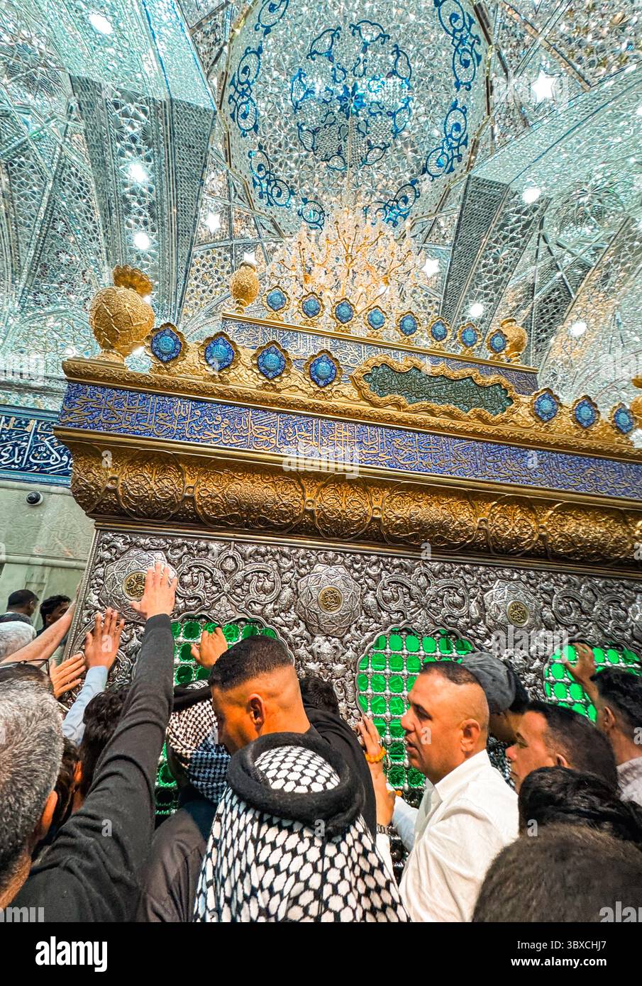 Un grande gruppo di individui si riunisce per rendere omaggio in un importante santuario di Karbala, Iraq, riflettendo profonde tradizioni culturali. Foto Stock