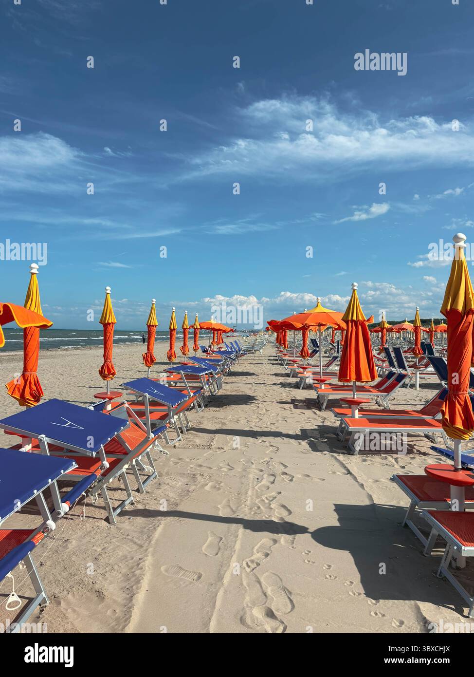 Spiaggia sabbiosa con lettini e ombrelloni senza persone. File di sdraio vuote sulla sabbia in una calda giornata di sole. Foto Stock