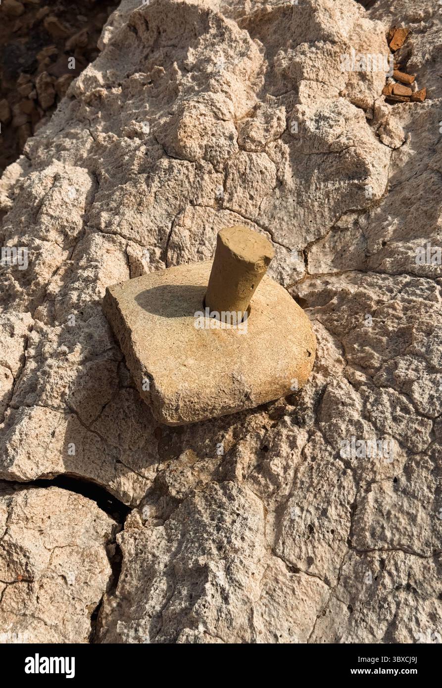 Un antico manufatto in pietra con una parte superiore cilindrica è posizionato su una superficie rocciosa incrinata e intemprata a Uruk Iraq. Foto Stock