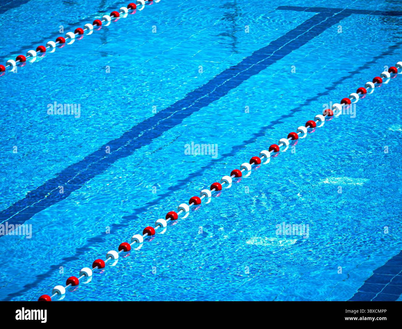 Piscina con divisori di corsia e acqua cristallina. Il pavimento piastrellato blu è visibile sotto la superficie, creando una rinfrescante scena di sport, i leis Foto Stock