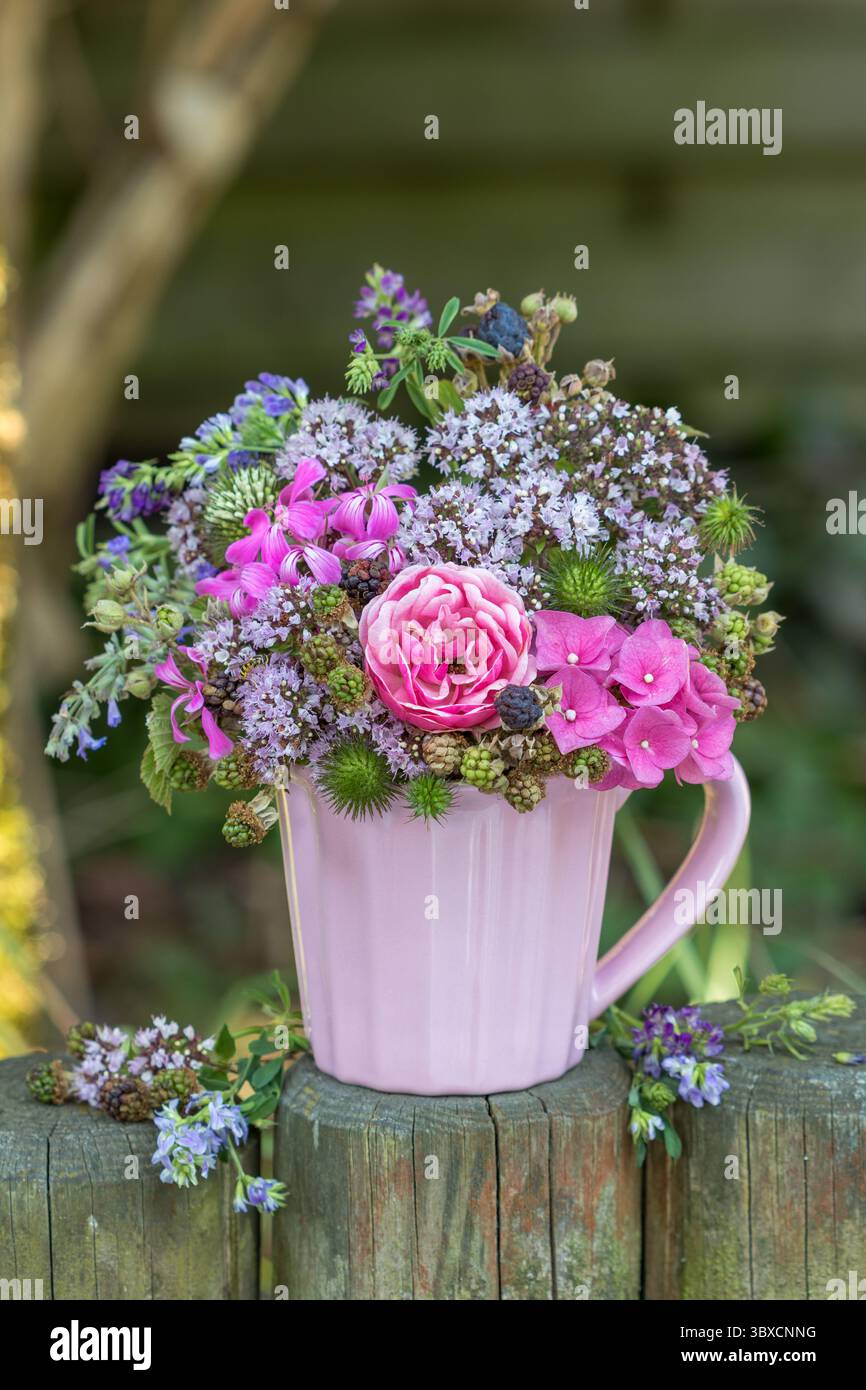 composizione floreale di rosa, ortensie, timo selvatico e more in una tazza di porcellana Foto Stock