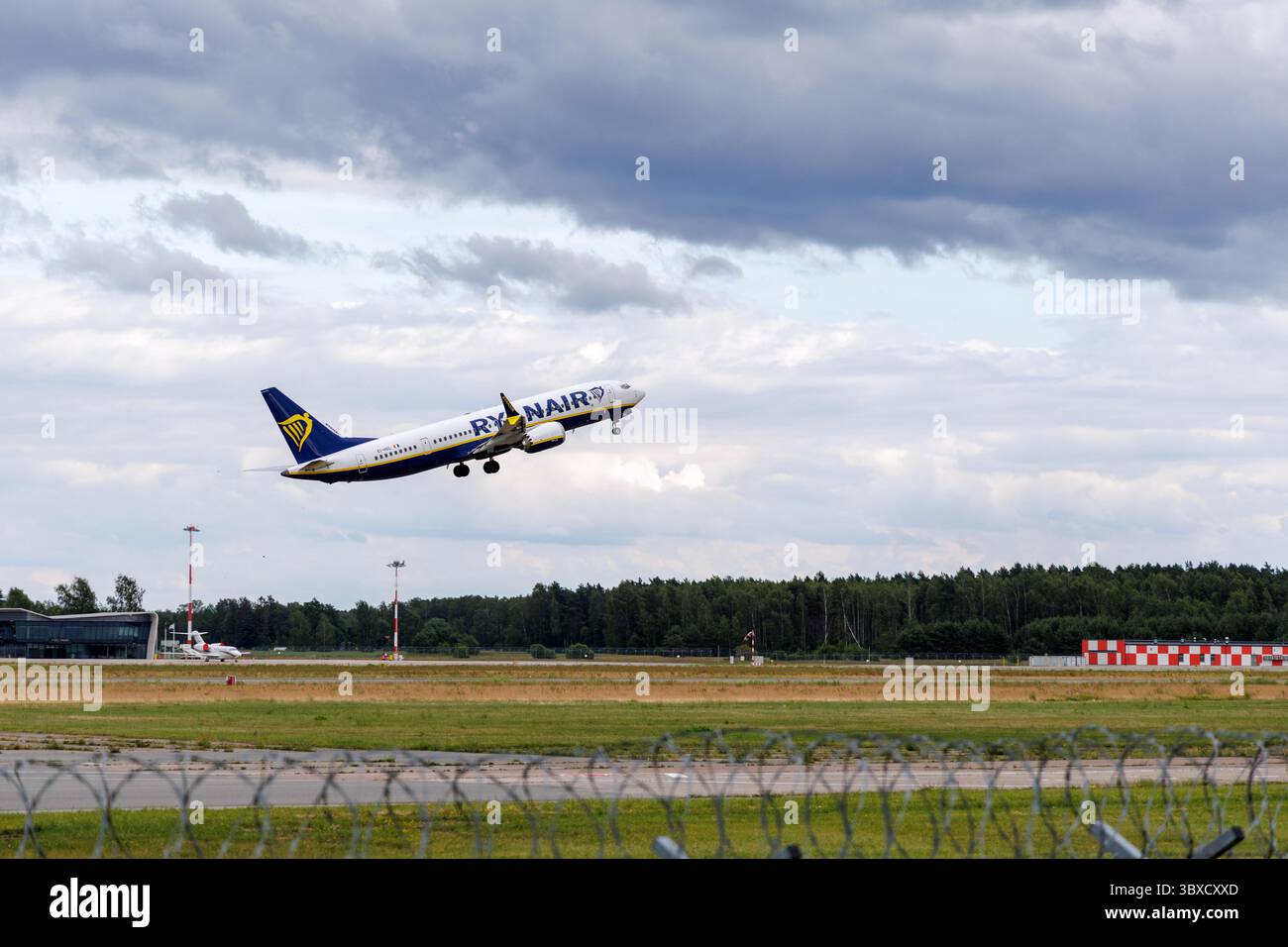 RIGA/LETTONIA – 07.06.2025: Un aereo Ryanair decolla dall'aeroporto internazionale di riga, contro un cielo nuvoloso, che rappresenta un viaggio europeo a prezzi accessibili. Foto Stock