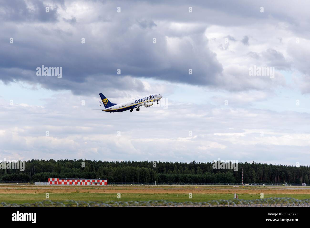 RIGA/LETTONIA – 07.06.2025: Un aereo Ryanair decolla dall'aeroporto internazionale di riga, contro un cielo nuvoloso, che rappresenta un viaggio europeo a prezzi accessibili. Foto Stock