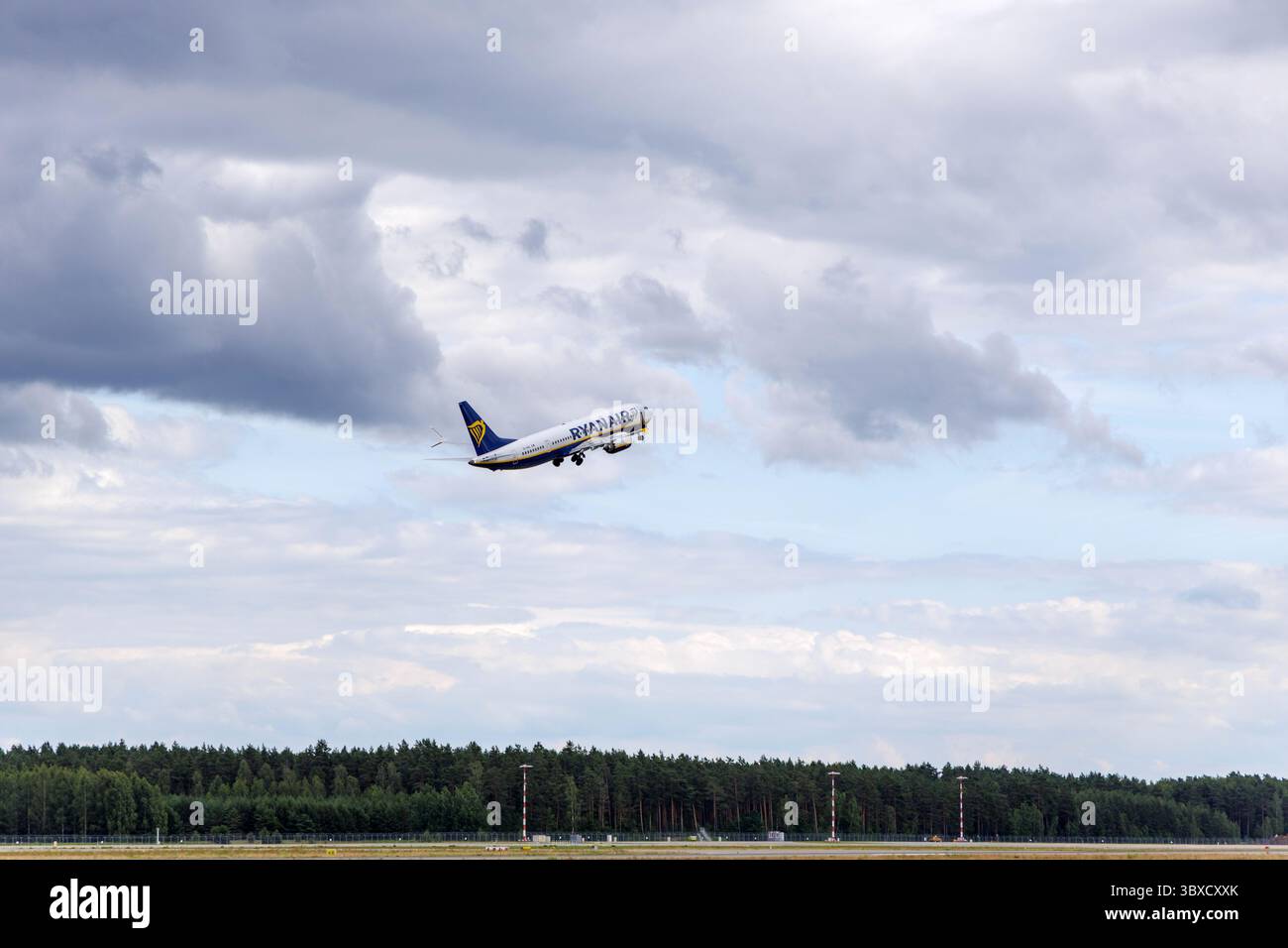 RIGA/LETTONIA – 07.06.2025: Un aereo Ryanair decolla dall'aeroporto internazionale di riga, contro un cielo nuvoloso, che rappresenta un viaggio europeo a prezzi accessibili. Foto Stock