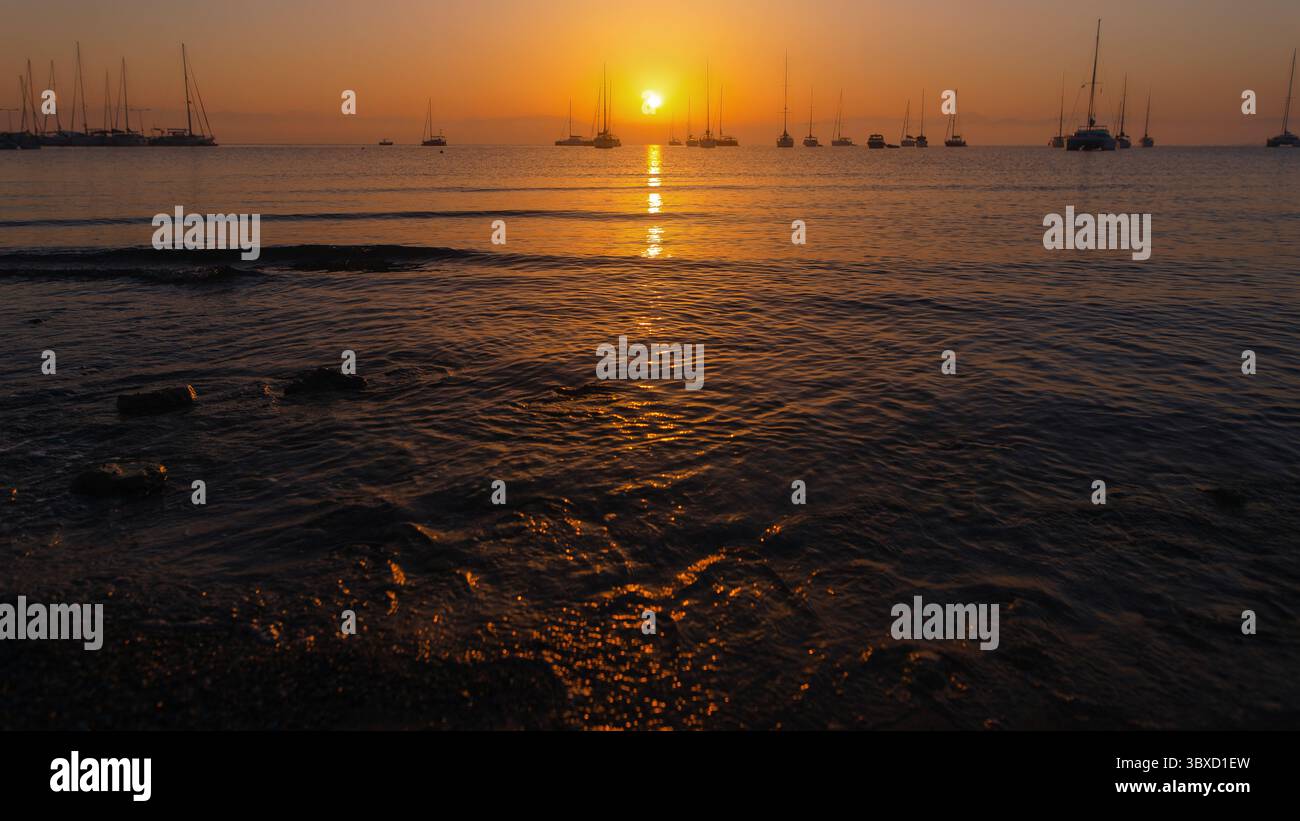 Calmo tramonto sul mare calmo con barche a vela Foto Stock