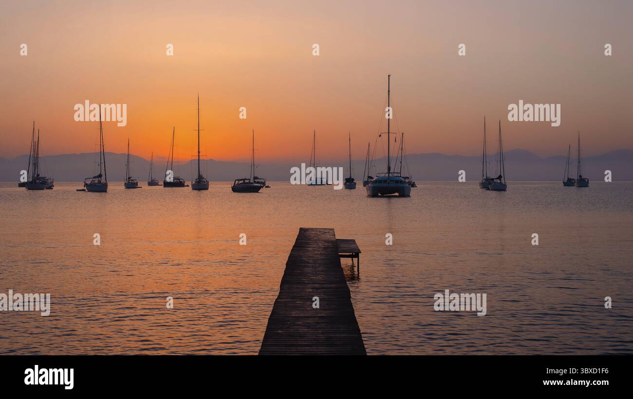 Tramonto sul mare calmo con barche a vela Foto Stock