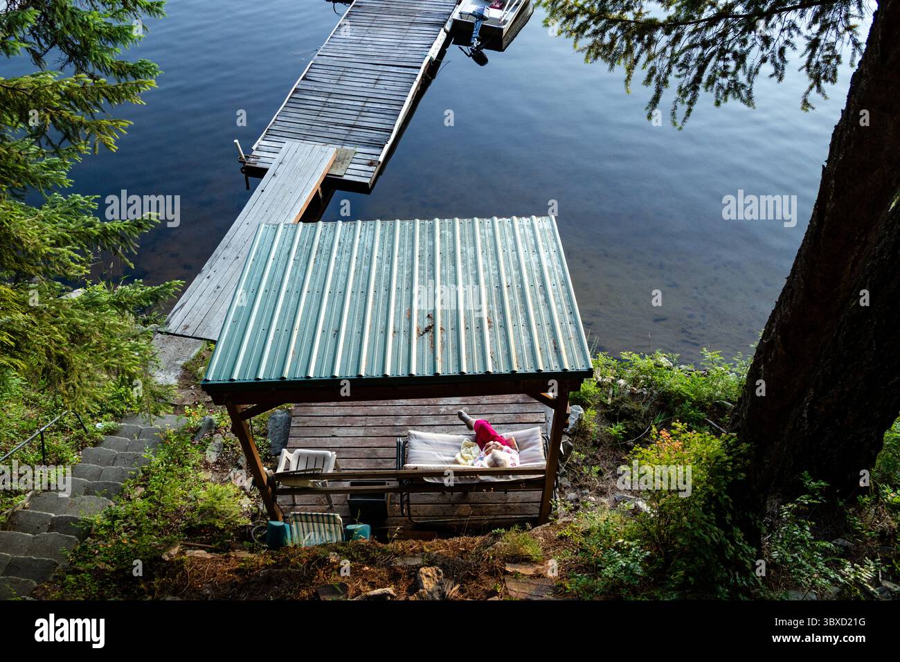 Persona che si rilassa sotto il riparo sul lago presso il molo di legno Foto Stock