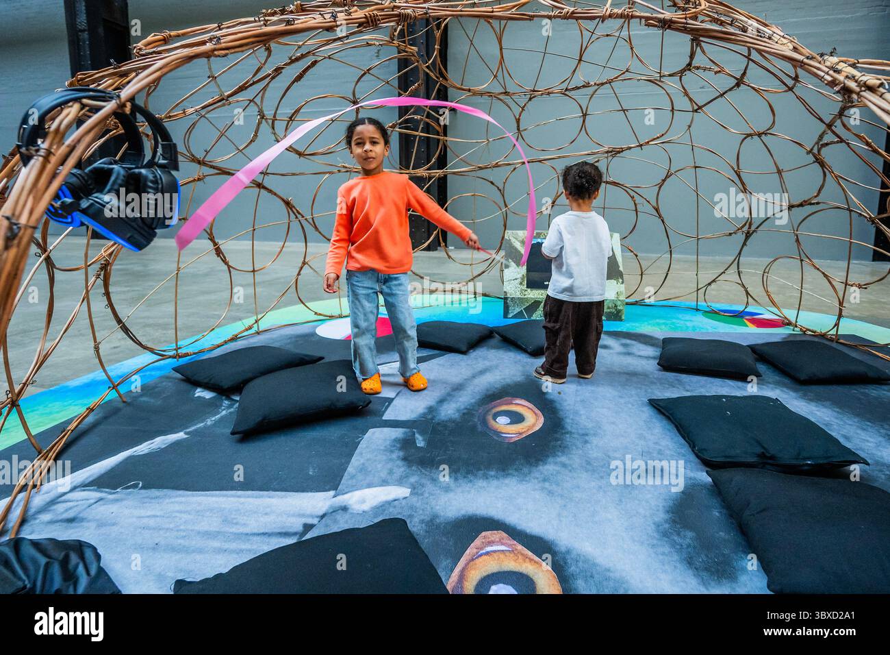 Londra, Regno Unito. 18 luglio 2025. I bambini sono attratti dagli schermi nelle cupole di ascolto: Tuono, crackle e magia The UNIQLO Tate Play: Monster Chetwynd at Tate Modern. Si tratta di una nuova installazione interattiva nella turbine Hall, ispirata al film di Ingmar Bergman del 1975 il flauto magico. L'esperienza giocosa si svolge in tre fantastici set, ognuno dei quali presenta uno spettacolo vivente di artisti, creature, costumi e oggetti di scena artigianali. I visitatori sono incoraggiati a spostarsi avanti e indietro tra il palco centrale e il dietro le quinte. È aperto dal 19 luglio al 25 agosto 2025. Crediti: Guy Bell/Alamy Live Foto Stock
