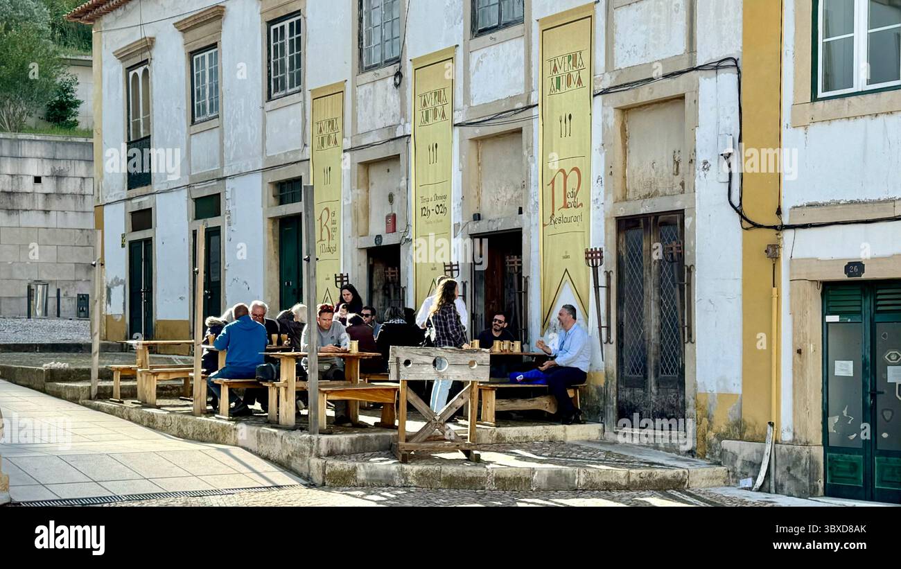 Persone sedute su panche di legno all'aperto che bevono in un bar di Tomar Portogallo - Immagine stock catturata con smartphone