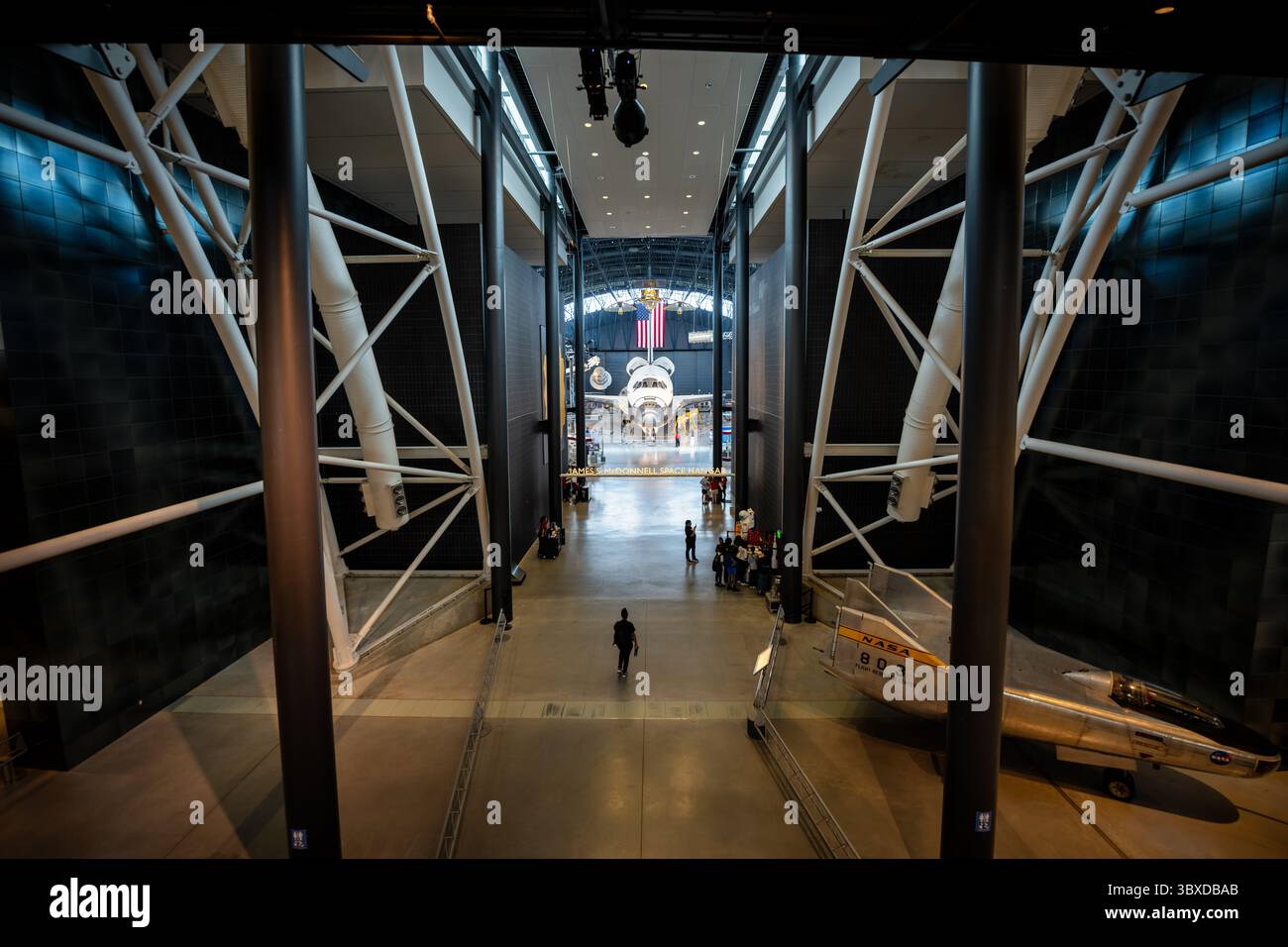 Space Shuttle Discovery display presso lo Steven F Udvar-Hazy Center a Chantilly Virginia | CHANTILLY, Virginia - i visitatori camminano verso lo Space Shuttle Discovery all'interno del James S. McDonnell Space Hangar, con un jet di ricerca NASA F-104 visibile sulla destra. Discovery è l'orbiter più volato della NASA, completando 39 missioni tra il 1984 e il 2011, ed è stato il fulcro dello Steven F. Udvar-Hazy Center dello Smithsonian dal 2012. L'hangar mostra anche una serie di razzi e satelliti tratti dalla collezione spaziale del museo. Foto Stock