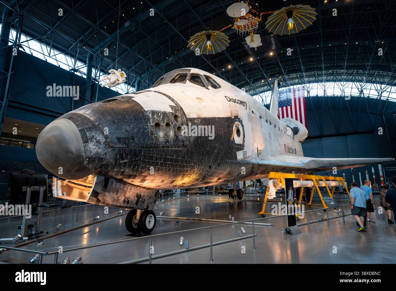 Space Shuttle Discovery display allo Steven F Udvar-Hazy Center di Chantilly Virginia | CHANTILLY, Virginia - il naso smussato e le finestre della cabina di pilotaggio dello Space Shuttle Discovery si innalzano sopra i visitatori allo Steven F. Udvar-Hazy Center, il suo cappuccio rinforzato in carbonio e le piastrelle anteriori oscurate dal ripetuto rientro atmosferico. Discovery ha effettuato 39 missioni tra il 1984 e il 2011, la maggior parte di qualsiasi orbiter dello Space Shuttle, e ha servito due volte come veicolo "Return to Flight" della NASA dopo il disastro. È esposto qui dal 2012. Foto Stock