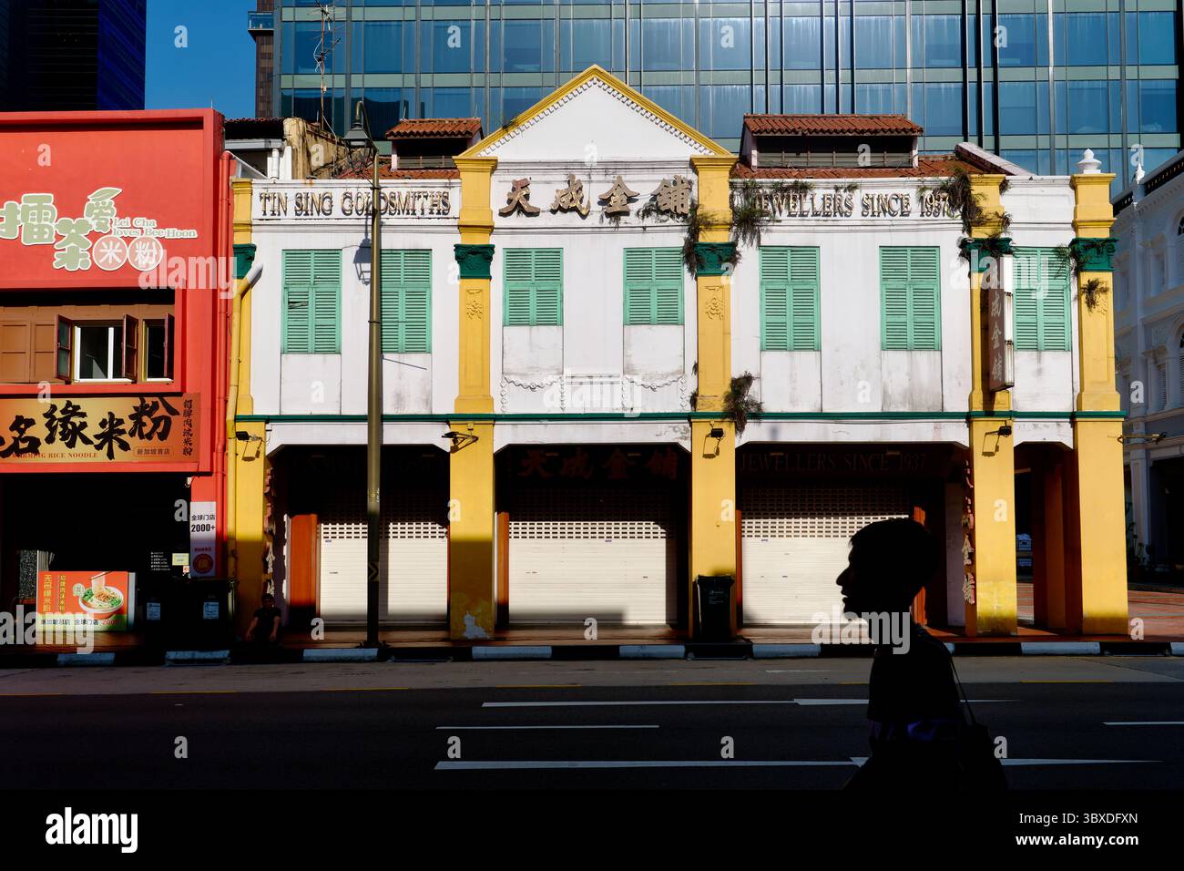 Edificio storico di proprietà di Tin Sing Goldsmiths in South Bridge Road, Chinatown, Singapore, una silhouette di un pedonale che passa davanti Foto Stock