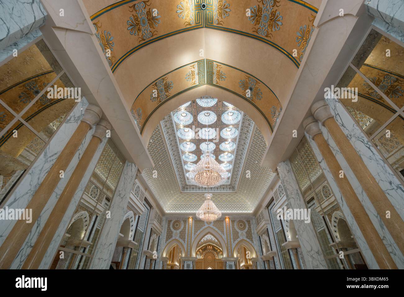 Eleganti interni architettonici con soffitti decorati, colonne e lampadari. Decorazioni lussuose con motivi floreali che riflettono un grande stile Foto Stock