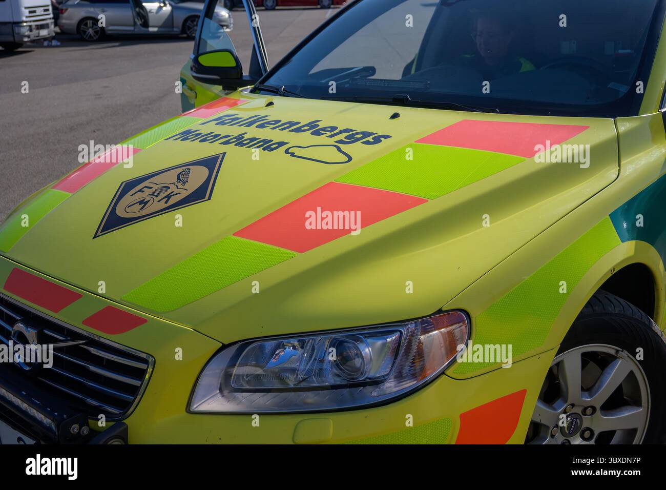 Un veicolo di emergenza giallo brillante e verde è parcheggiato in un'area urbana. I contrassegni riflettenti risplendono sotto il sole di mezzogiorno, sottolineando la sua disponibilità Foto Stock